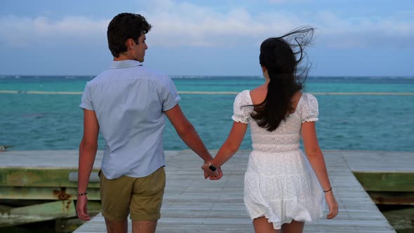 Romantic date theme. Boy and girl holding hands. Tropical island destination getaway wedding honeymo