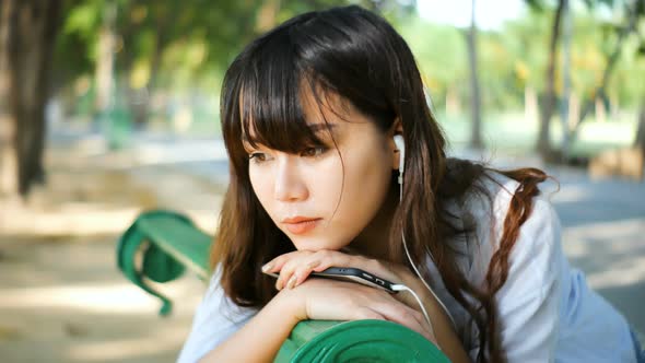 young hipster sad asian woman emotionally listening music in headphones with smartphone.