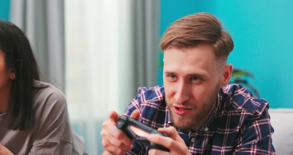 American Excited Man Sitting on a Sofa Holding a Joystick Playing Video Games Feeling Overjoyed