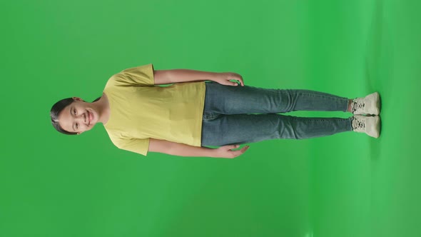 Full Body Of Young Asian Kid Girl Warmly Smiling On Green Screen Background In The Studio
