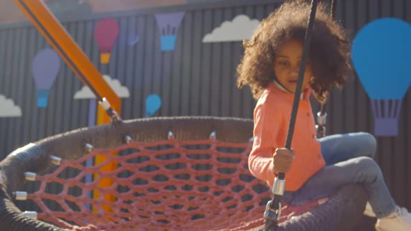 Close Up of African Children Ride on Round Swing with Net in Park