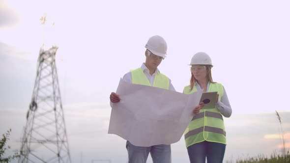 A Group of Engineers at a Highvoltage Power Plant with a Tablet and Drawings Walk and Discuss a Plan