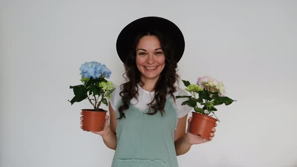 Beautiful Young Florist Woman Dancing with Flowers on White Background Smiling at Camera