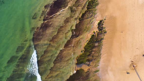 Amazing scenic drone view of the beach and ocean with calm waves during a sunset with vibrant colors