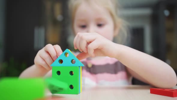 a Cute Little Girl Builds Houses From a Colorful Wooden Construction Set