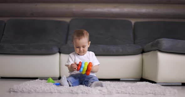 Cute Little Baby Boy Playing with Colorful Pyramid Toy at Home