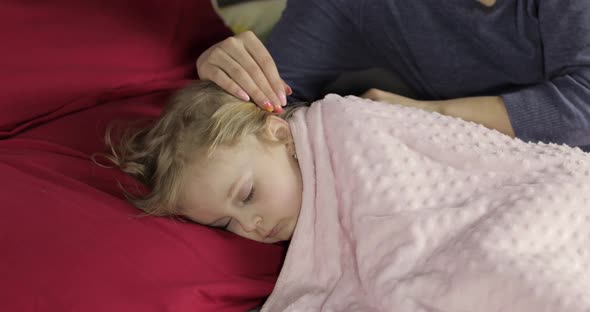 Young Mother Taking Care of Her Little Baby Girl While She Sleep. Girl on Bed