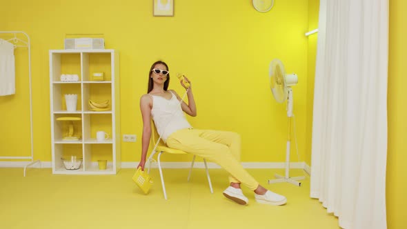 Young Woman Is Sitting In Office Chair And Holding Retro Telephone