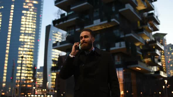 Young handsome caucasian bearded businessman talking smartphone