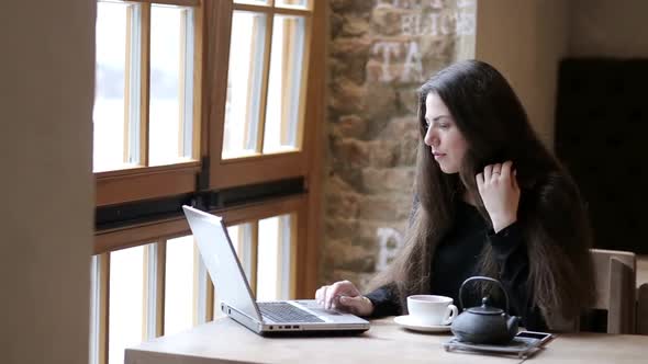Woman working on laptop and smiling, business lady sitting in cafe