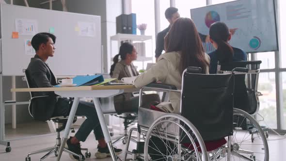 A disabled company employee is able to work happily with colleagues in the office.