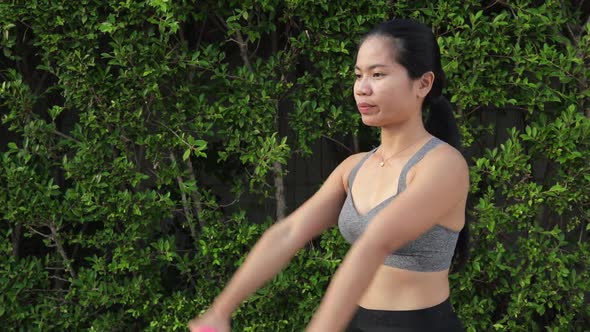 Sporty Thai Woman Exercising With Dumbbells Stretching Arms Forward And Sideways. - medium shot