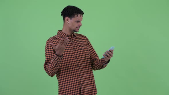 Happy Young Handsome African Man Using Phone and Looking Surprised