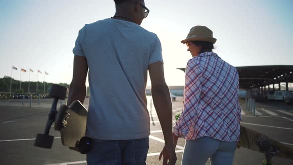 Young Attractive Mixed Race Couple Riding Skateboards and Having Fun Slow Motion