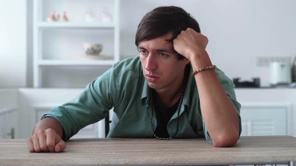 Portrait of Worried and Stressed Young Man Sitting at Table at Home