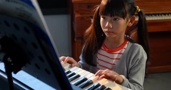 Schoolgirl learning electric piano in music class 4k