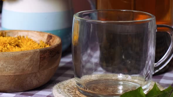 Dandelion Flower Healthy Tea in Glass Teapot and Glass Cup on Table