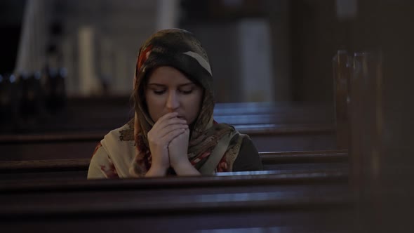 Young woman in headscarf praying