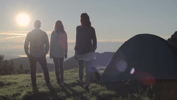 Young Friends Doing Camping Looks at Sun in Mountain Outdoor Nature Scenery During Summer Sunrise or