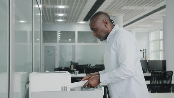 African American Senior Adult Business Man Refills Paper in Printer Office Equipment Electronic