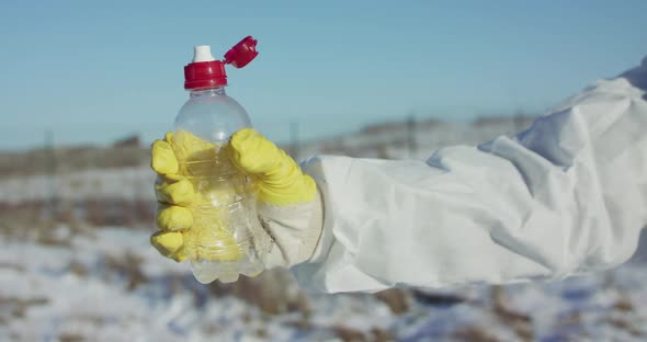 Male Hand in Protective Costume and Glove Constricts Plastic Bottle