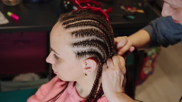 Unrecognizable Person Makes Hairstyle for Young Woman in Salon