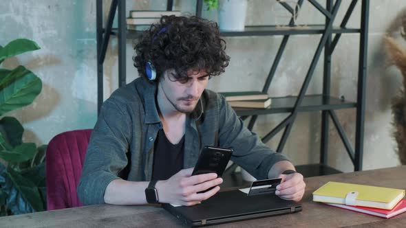 Young Man Shopping Online with Credit Card Using Smart Phone at Home