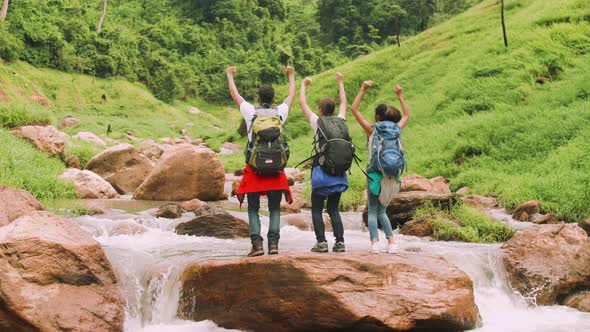 A group of trekkers with backpacks proudly arrived at their destination in beautiful nature.