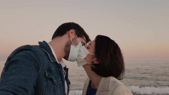 Couple kisses with mask on the beach