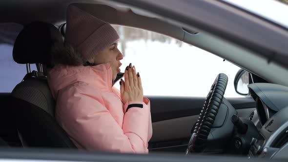 Female Blowing on Hands Trying to Get Warm in Car