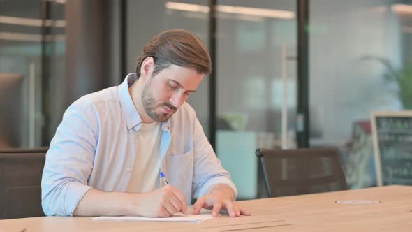 Mature Adult Man Facing Difficulty While Writing on Paper