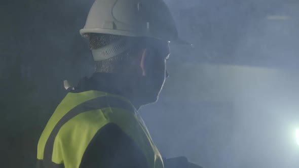 Serious Man in the Builders Uniform and Helmet Standing in Front of the Black Background with