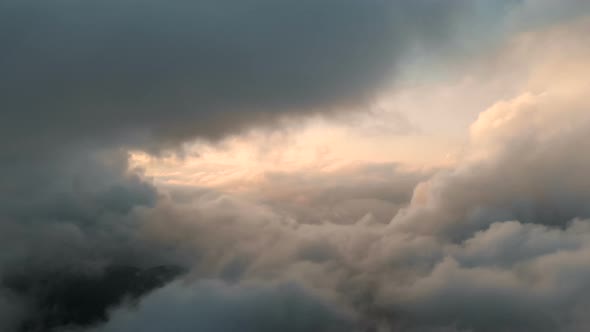 Aerial View Flying Through Cumulus Thunderclouds at Sunset. Gold Colored Sunset Cloudiness in High