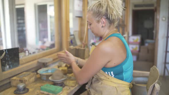 Woman Potter Taking Some Clay From Bucket for Work and Putting It on Potters Wheel