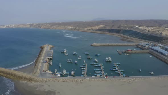Aerial view, circling around a port with small to medium boats anchored inside