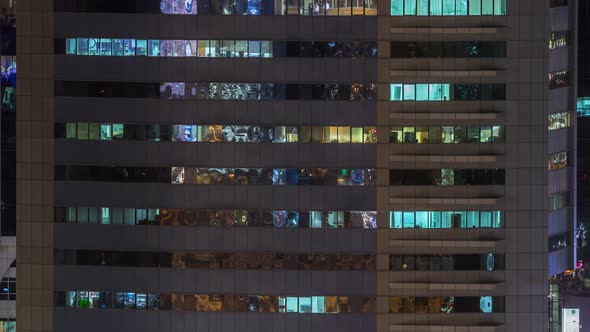 Windows of the Multistorey Building of Glass and Steel Lighting Inside and Moving People Within