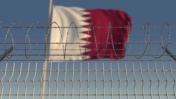 Waving Flag of Qatar Behind Barbed Wire Fence