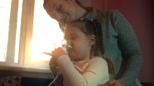 Beautiful Little Girl Makes Inhalation Using a Compressor Inhaler While Sitting on a Sofa