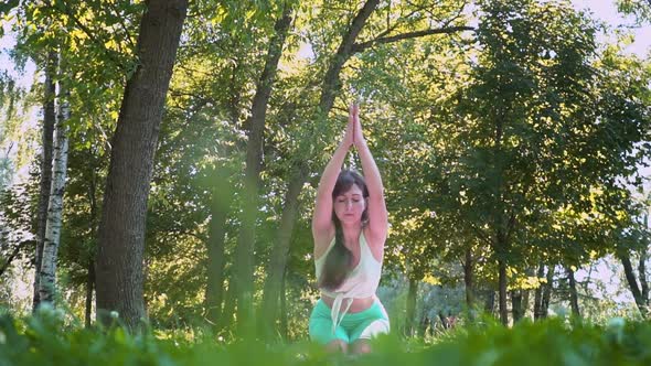 Meditating Outdoors Beautiful Young Yogi Woman Enjoying Relaxing on a Green Meadow in Sunny Weather