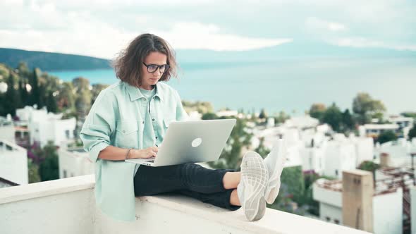 Young Woman Freelancer Working with Her Laptop on the Roof Terrace.