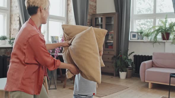 Asian Mom and Son Pillow Fighting in Living Room