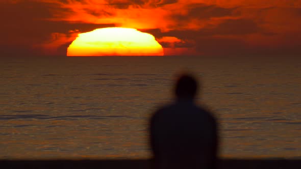 Silhouette of a man watching the sunset at the beach.