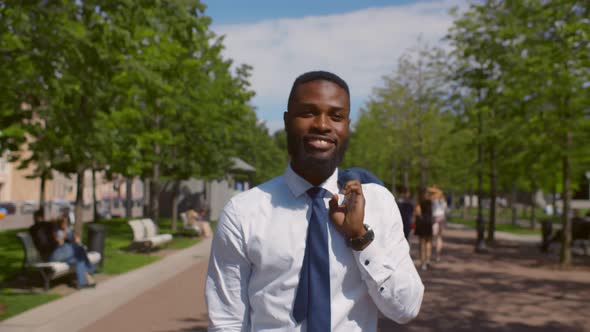 Portrait of African Businessman Walking with Jacket Dropped Over Shoulder in Park