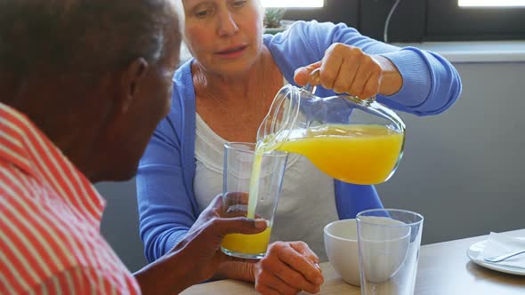 Senior woman pouring juice into glass to her friend 4k