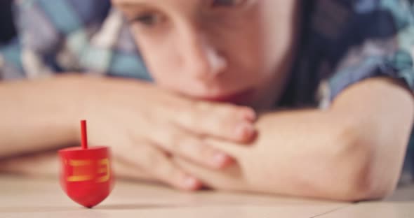 Close up shot of a boy spinning a Hanukka dreidel on the floor