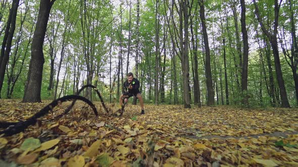 Sportsman doing waves with battle ropes in the autumn forest. Athletic man in black sportswear is tr