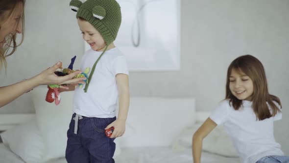 adorable mother and her children, daughter and little son play toys on fingers