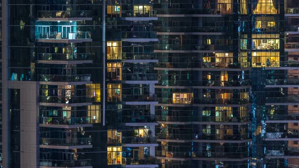 Glowing Windows in Multistory Modern Glass Residential Building Light Up at Night Timelapse