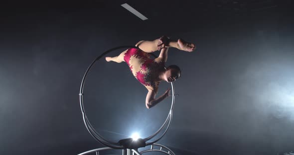 Skillful Gymnast is Doing an Upside Down Split on a Steel Hoop