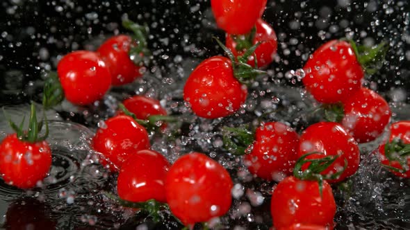 Super Slow Motion Shot of Cherry Tomatoes Flying Into Water on Black Background at 1000Fps